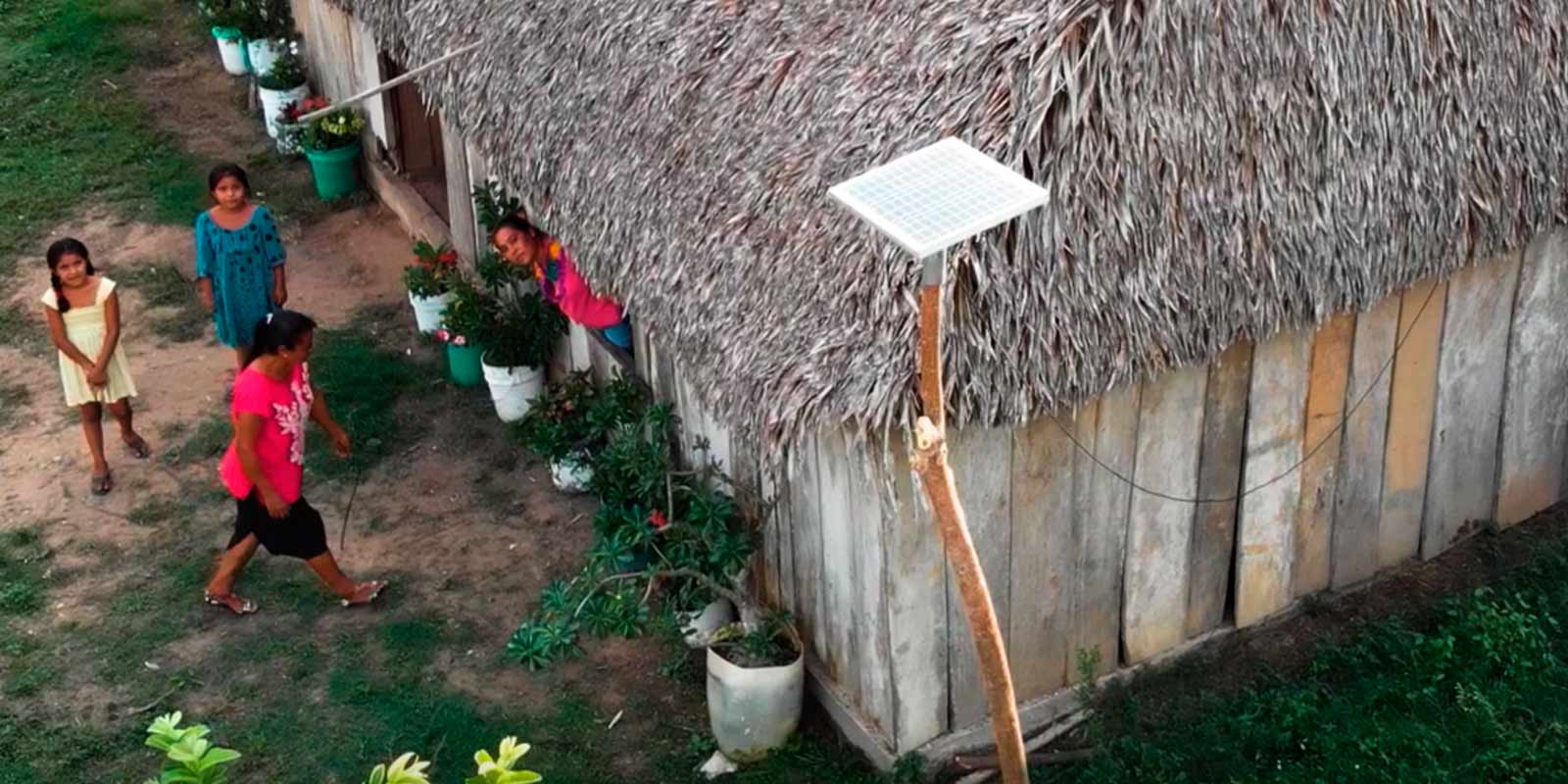 vista aérea de mujeres entrando a su hogar y un panel solar de la fundación acciona.org